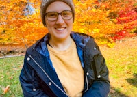 Steph smiling in front of the fall foliage
